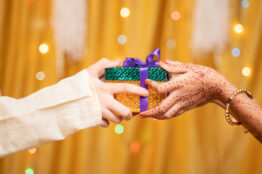 Close up of Brother Hands Giving gift to sister during during raksha Bandhan, Bhai Dooj or Bhaubeej Indian religious festival .
